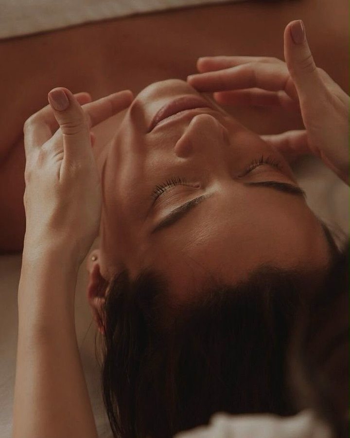 Hands framing a client's face during a sculpting facial massage